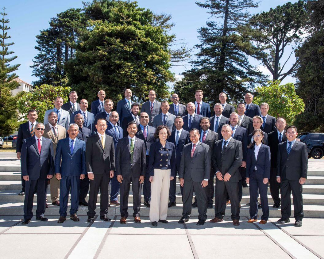 group of people in formal attires standing in front of beautiful green trees