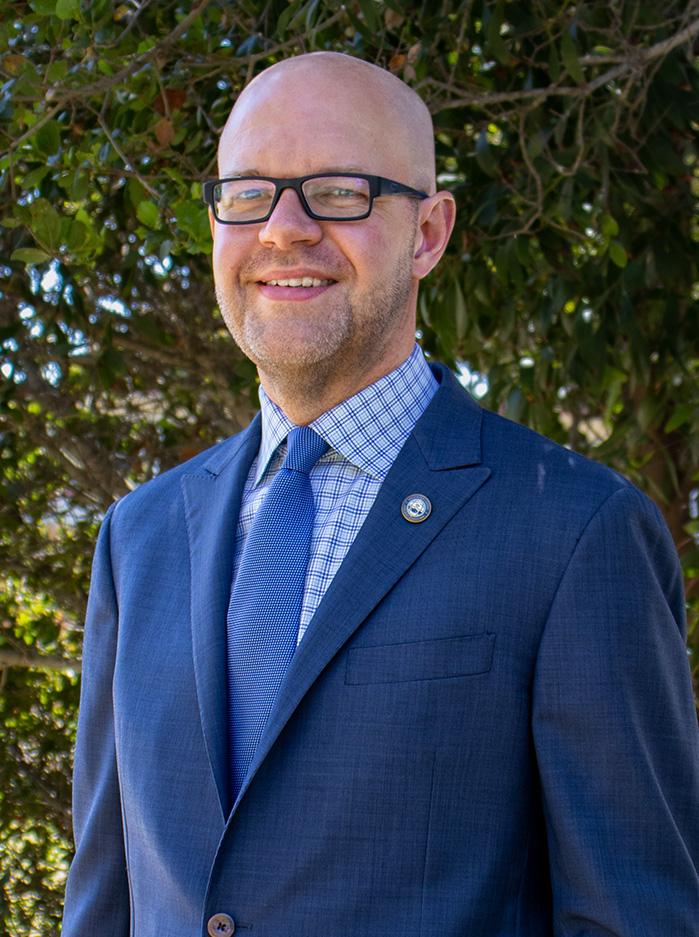 bald man in glasses wearing a blue suit